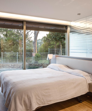 Sypialnia z dużymi oknami oraz z dużym tapicerowanym łóżkiem kontynentalnym