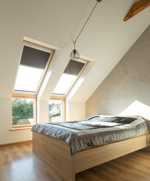 Sypialnia na poddaszu z drewnianymi belkami na suficie