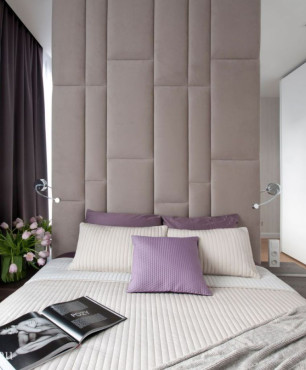 Przytulna sypialnia z tapicerowanym panelem na ścianie za łóżkiem kontynentalnym