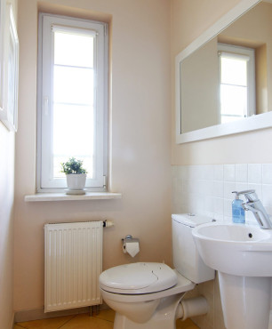 Toaleta z białym zlewem wiszącym oraz dużym lustrem w białej ramie
