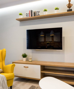 Salon z podłużną szafką pod telewizorem oraz z żółtym fotem uszak