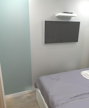 Mała sypialnia z telewizorem na ścianie oraz jasnymi panelami na podłodze