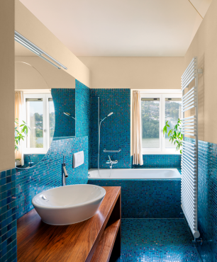 Wyjątkowa łazienka z oknem oraz wanną zabudowaną z niebieską mozaiką na ścianie i podłodze