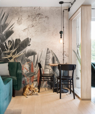 Salon z kącikiem jadalnianym oraz z tapetą z motywem botanicznym na ścianie