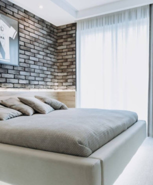 Sypialnia z cegłą na ścianie oraz z łóżkiem drewnianym kontynentalnym
