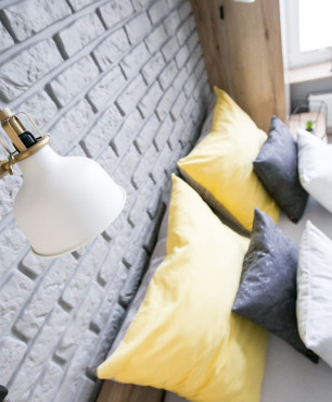 Sypialnia z szarą cegłą na ścianie oraz lampką nocną w stylu retro