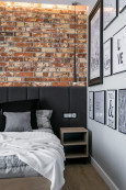 Sypialnia w stylu industrialnym z cegłą na ścianie oraz z tapicerowanymi panelami
