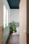 Sypialnia z biało-zielonym kolorem farby na ścianie oraz ze wzorzystymi płytkami na podłodze