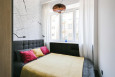 Sypialnia z szarym łóżkiem kontynentalnym, tapetą na ścianie oraz modną lampą wiszącą