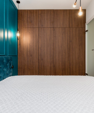 Sypialnia z drewnianą szafą w zabudowie pod sufit oraz z turkusowym kolorem ścian ze sztukaterią