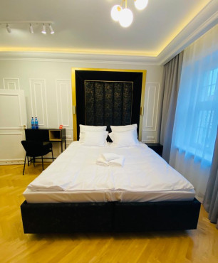 Nowoczesna sypialnia hotelowa z dużym, tapicerowanym łóżkiem kontynentalnym z czarnym tapicerowanym zagłówkiem