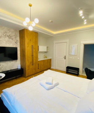 Sypialnia hotelowa z dużym łóżkiem, telewizorem na ścianie, biurkiem oraz kącikiem kawowym