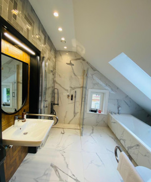 Duża łazienka na poddaszu hotelowym z zabudowaną wanną akrylową