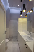 Nowoczesna łazienka z prysznicem oraz czarnymi lampami wiszącymi