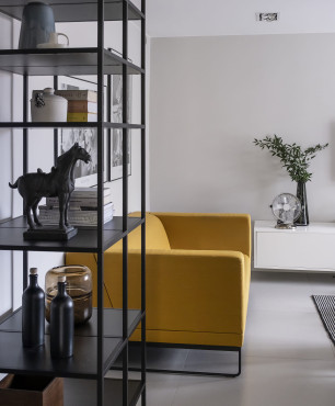 Salon z żółtą sofą oraz czarnym regałem w stylu loft