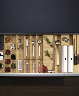 Kuchnia z drewnianym organizatorem w szufladach oraz ciemnymi panelami na podłodze