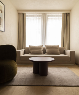 Salon z designerskim fotelem w ciemnym kolorze oraz z jasną sofą